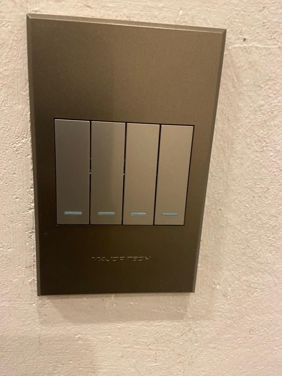 Four-lever brushed metal light switch neatly installed on a plastered wall by Happ's Electrical