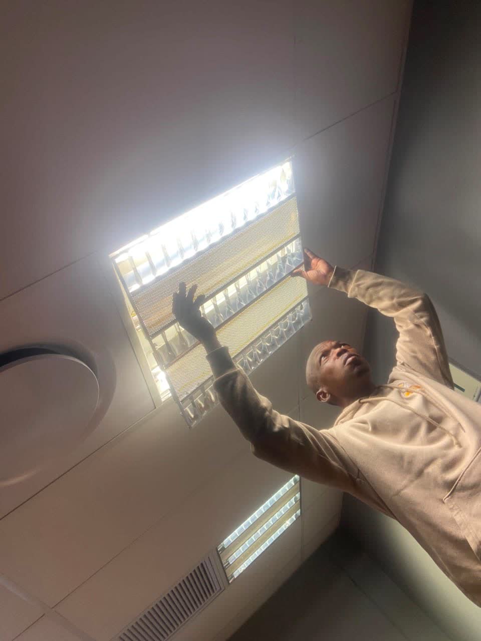 Happ's Electrical technician servicing a recessed office ceiling panel light in a commercial building